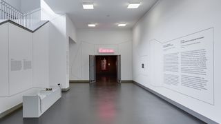 Bilck auf den Eingang des Ausstellungsraumes. Über der Eingangstür ein leuchtend, pinkes Reclameschild mit der Aufschrift &quot;C'est la vie&quot;.